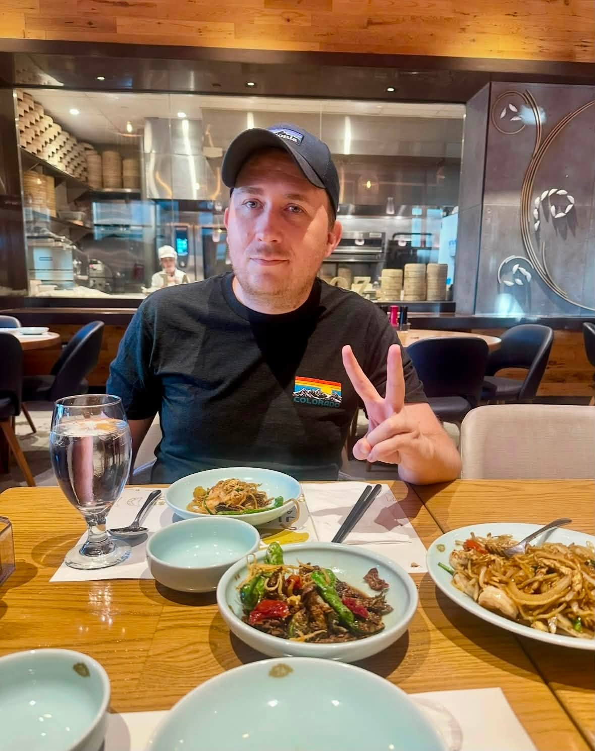 Brandon PT Davis at dinner, smiling and holding up a peace sign