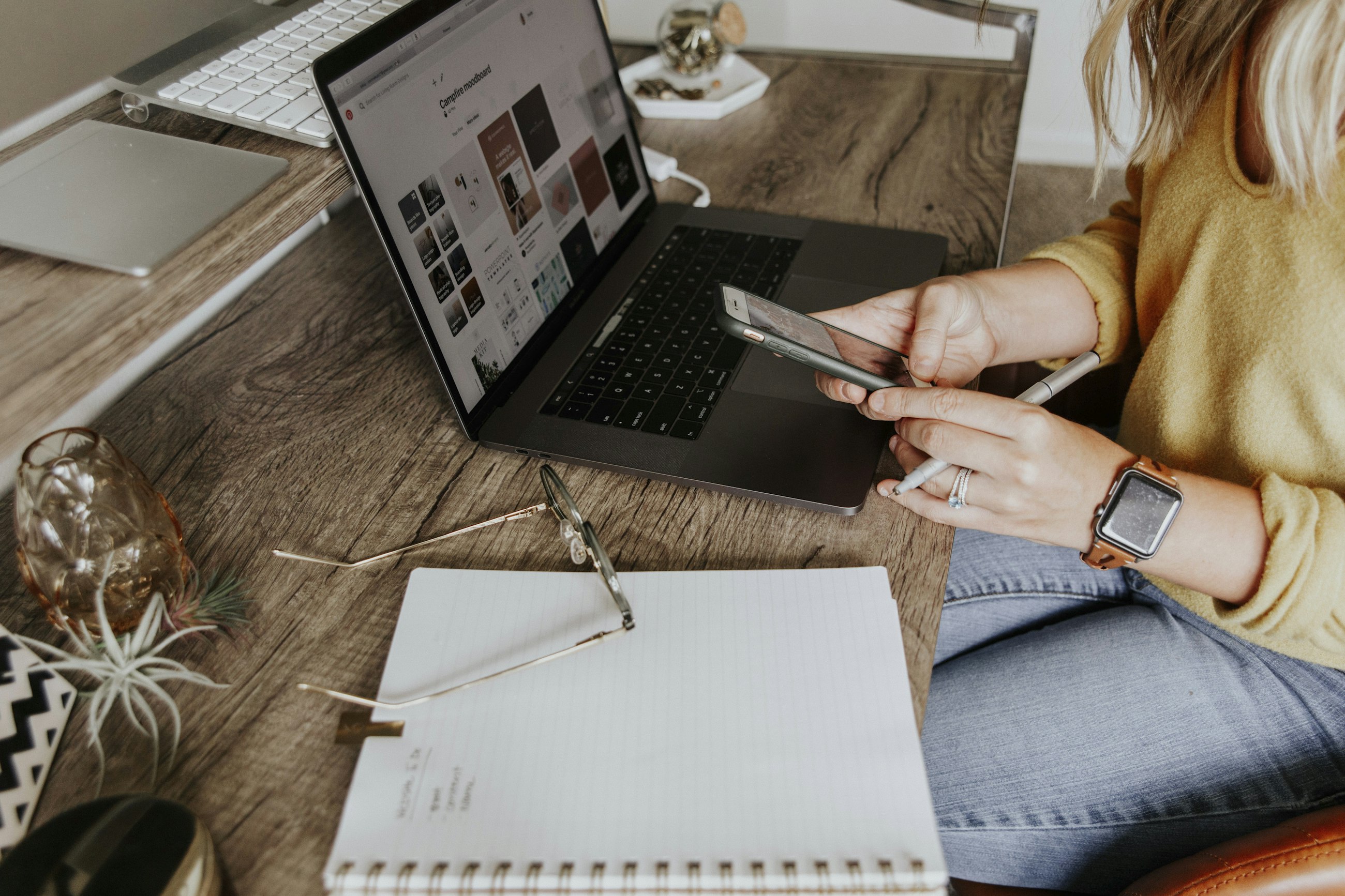 A creative professional moving between a laptop, phone, and sketchbook
